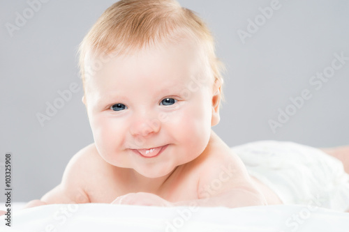 Portrait of a cute smiling infant baby crawling in a diaper.