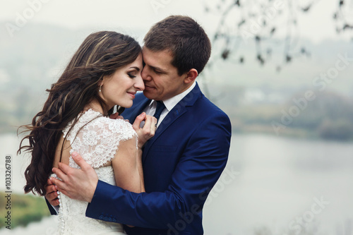 Happy beautiful couple of newlyweds hugging near romantic lake