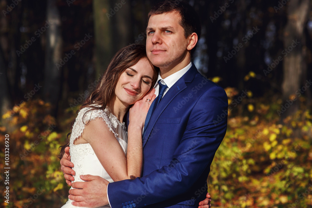 Romantic, happy newlywed couple hugging in autumn park at sunset Romantic, happy newlywed couple hugging in autumn park at sunset