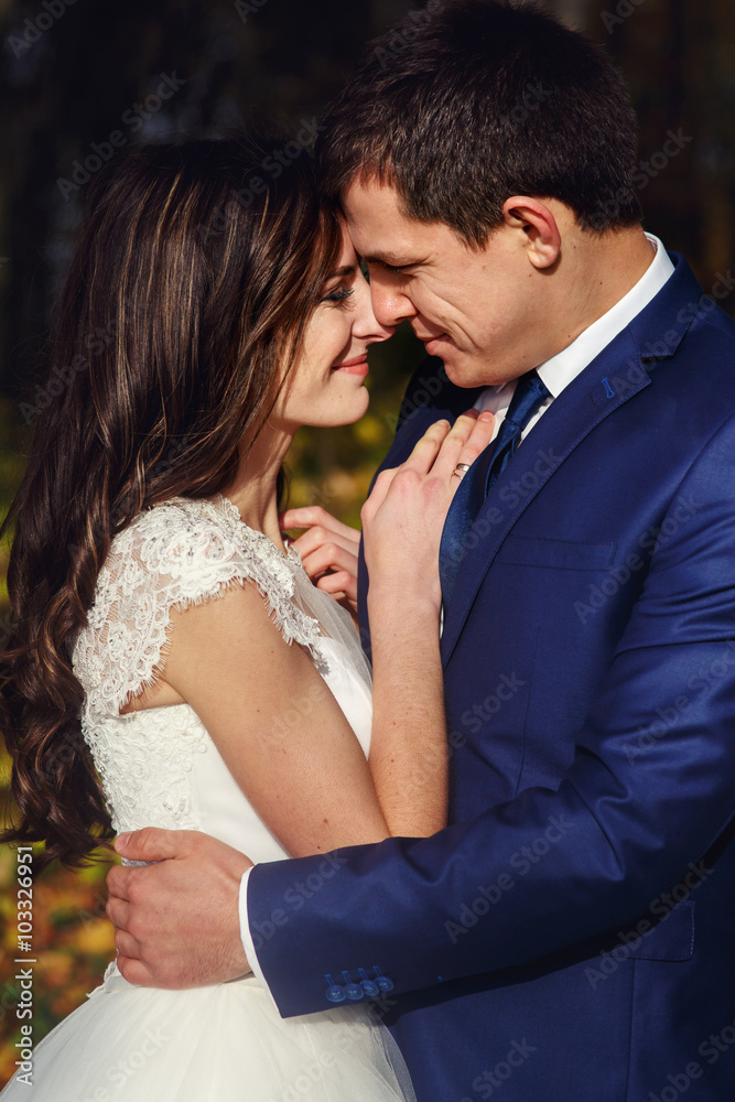 Romantic, happy newlywed couple hugging in autumn park at sunset Romantic, happy newlywed couple hugging in autumn park at sunset