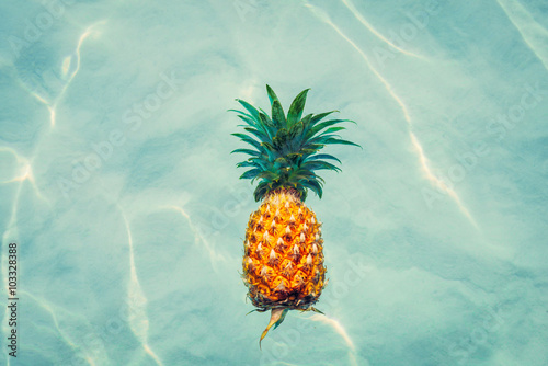 Pineapple into water on sunny beach