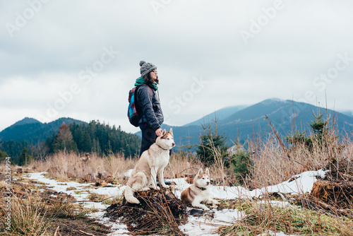 female hiker with siberian husky dogs in mountains looking at beautiful view