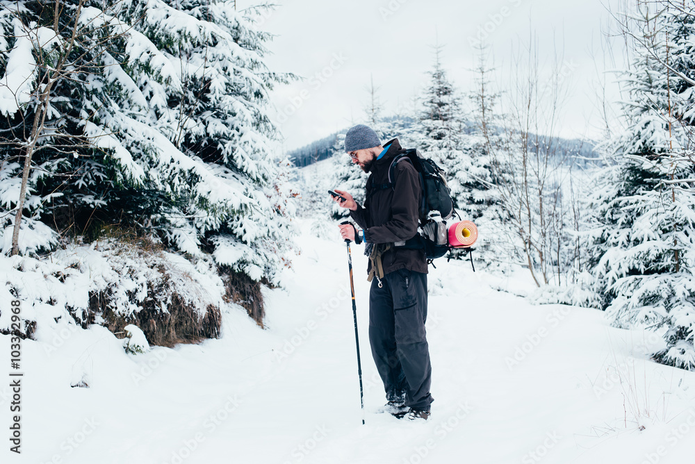 hiker with cellphone in snowy mountains