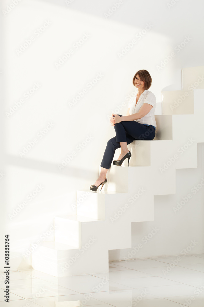 Elegant adult woman smiling while sitting on steps