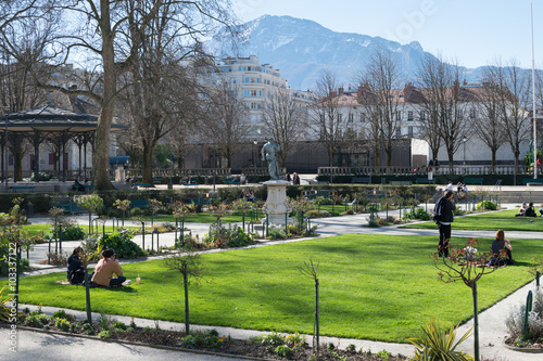 Square, herbe et gens assis dans le Jardin de ville à Grenoble, lors d'un dimanche d'hiver ensoleillé, plan large
