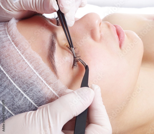 young beautiful girl is getting eyelash extentions closeup