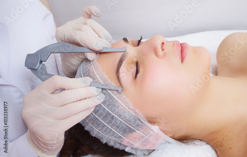 tattooist is using tool to measure eyebrows