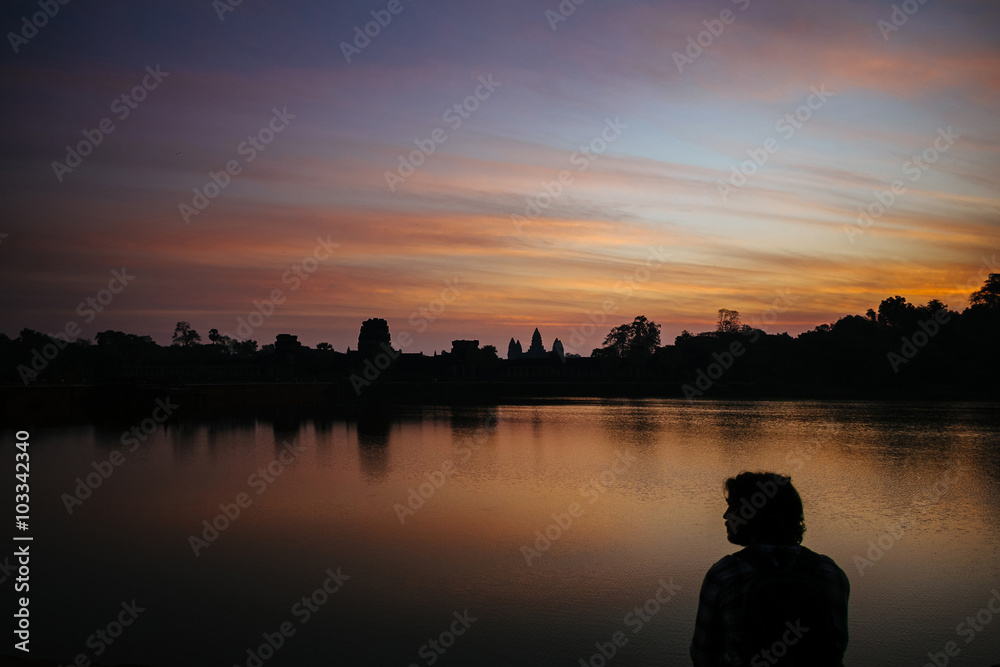 profile of a man against the backdrop of Angkor Wat at dawn