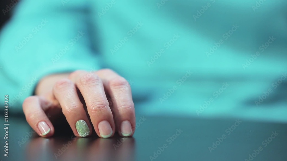 Women's hand with nice manicure nervously tapping fingers on the table