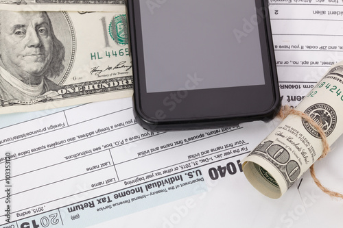 Money and cellphone on tax form background