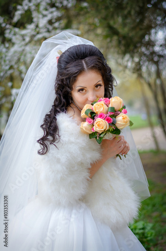 fiancee brunette in a wedding-dress with a bouquet photo