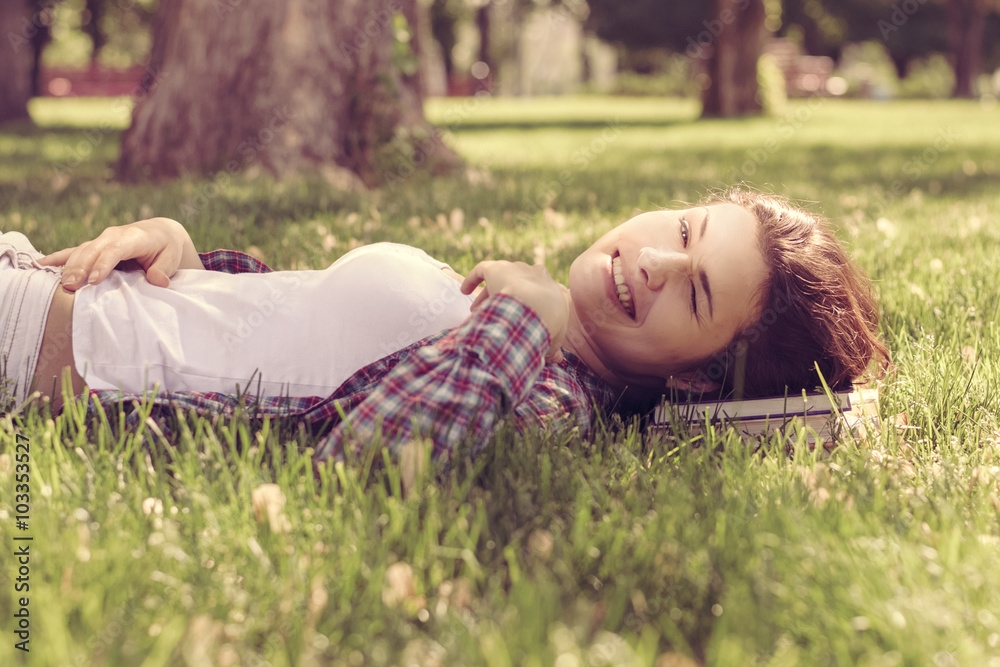 Student lying on the grass in the park resting her head on the b Student lying on the grass in the park resting her head on the b