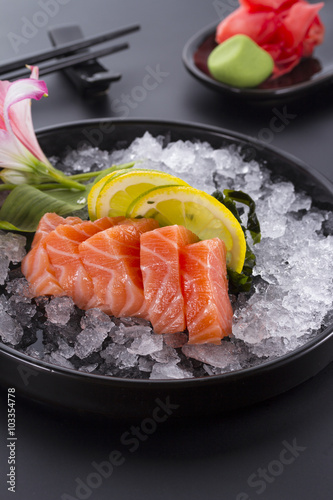 Salmon raw sasimi with ice on a black background