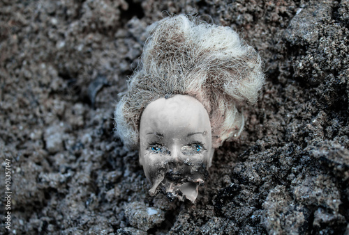 Foto Plastic scald doll head lying in a pile of dirt