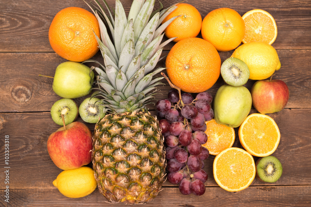 Tasty fruit background with orange, kiwi, grape, apples and lemon on the wooden table Tasty fruit background with orange, kiwi, grape, apples and lemon on the wooden table