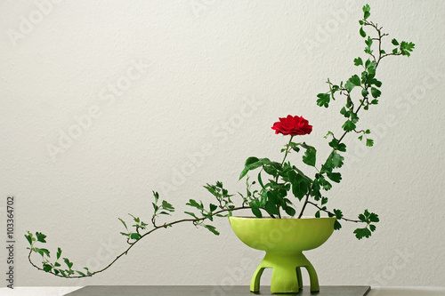 Ikebana mit roter Rose in gelber Vase