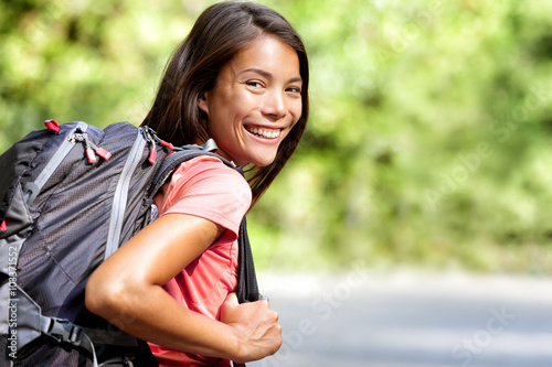 Happy young Asian Chinese backpack girl student. Cute adult woman backpacker smiling at camera with school bag doing summer backpacking travel in nature.