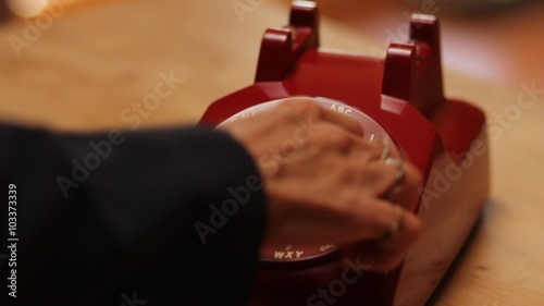 A woman frantically dials 911 on a vintage rotary phone