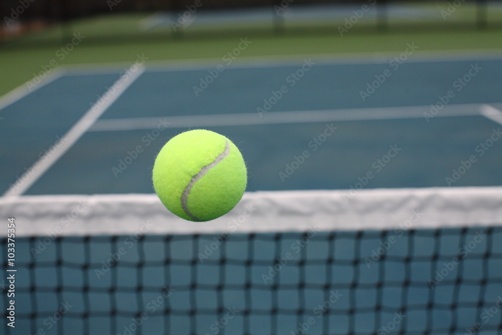 Tennis Ball Over Net on Blue Green Court