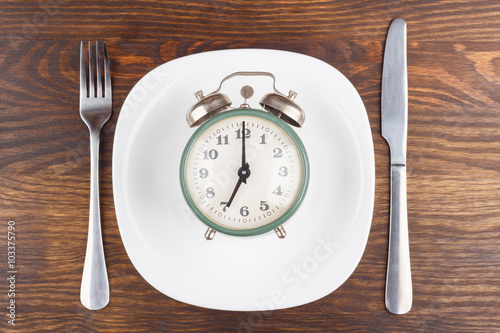 Vintage alarm clock on the plate, wooden background