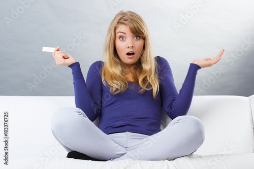 Shocked woman holding pregnancy test with positive result