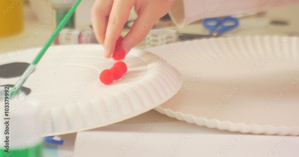 Childish Hand is Putting a Small Red Balls Plate White Disposable Dish Making a Snowman New Year's Winter Applique in a Classroom of Kindergarten Childish Hand is Putting a Small Red Balls Plate White Disposable Dish Making a Snowman New Year's Winter Applique in a Classroom of Kindergarten