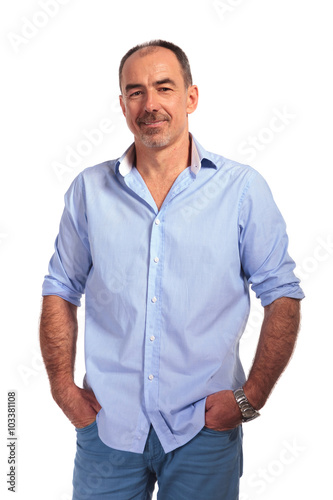 confident mature bald man posing smiling with hands in pockets