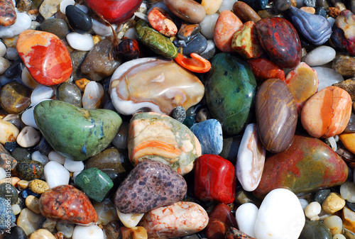 Multicolored sea pebbles in the wave on the shore for background or wallpaper.