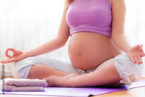 Pregnancy yoga. Young pregnant woman meditating in yoga pose at home.