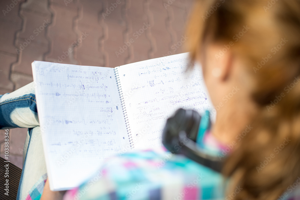 Student girl with copybook on bench. Summer campus park.