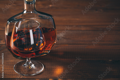 Glasses of cognac and bottle on the wooden table.