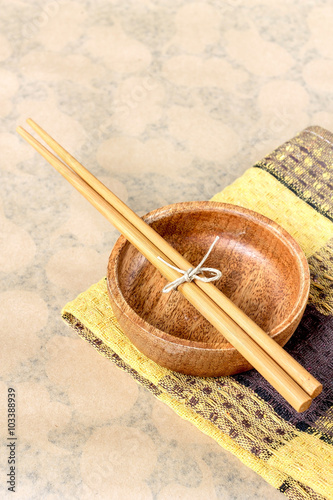 Chopsticks on wooden bowl on table linen on bright brown paper, table dining set with copy space