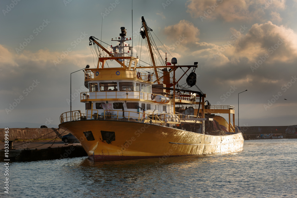 Yellow fishing boat moored to dock