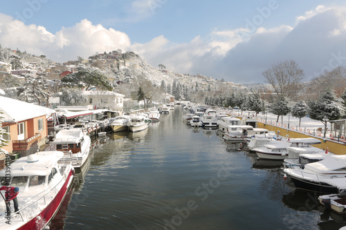 Boats and Yachts covered with snow parked on Goksu Rriver creates very nice landscape with the hill and the trees, Istanbul photo