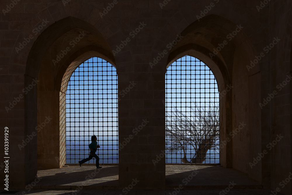 Unrecognizable girl runs in a backlit condition which creates nice silhouettes, Zinciriye Mosque in historical city of Mardin, Turkey