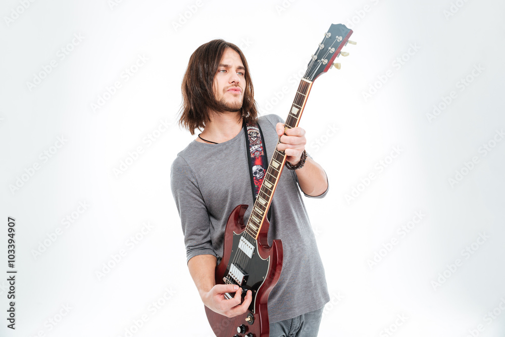 Attractive charismatic male guitarist standing and playing electric guitar Attractive charismatic male guitarist standing and playing electric guitar