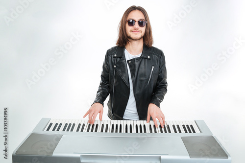 Photography Smiling man with long hair in sunglasses playing on synthesizer