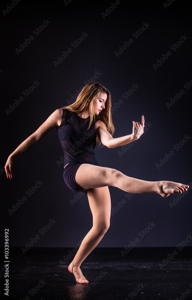 beautiful ballet dancer posing on black studio background