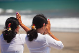 Two asian women with praying hands on ocean beach at ceremony Melasti before Balinese New Year and silence day Nyepi. Holidays, festivals, rituals, art, culture of Indonesian people and Bali island.