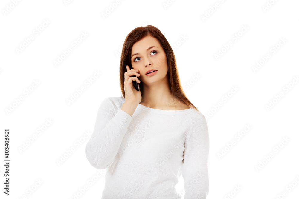 Thoughtful teen woman talking through a mobile phone Thoughtful teen woman talking through a mobile phone