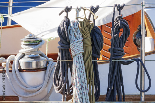 Colorful nautical accessories with ropes, pulley and chromed winch on a well equipment wooden sailboat