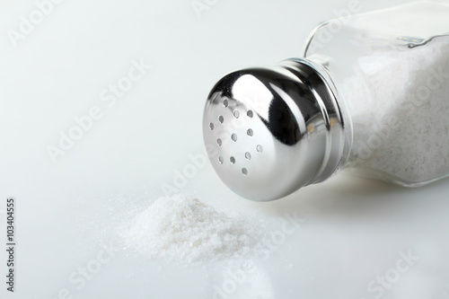 salt in a glass bottle and scattered on white isolated background