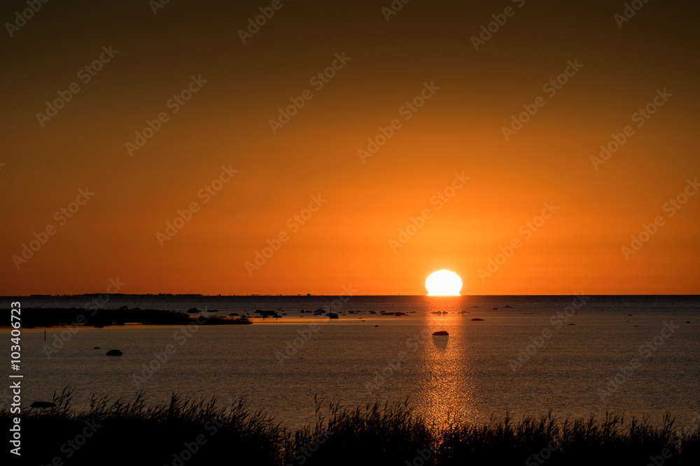 Sunset rocky beach, peaceful sea, orange sky. Kihnu, small island in Estonia. Baltic sea, Europe Sunset rocky beach, peaceful sea, orange sky. Kihnu, small island in Estonia. Baltic sea, Europe