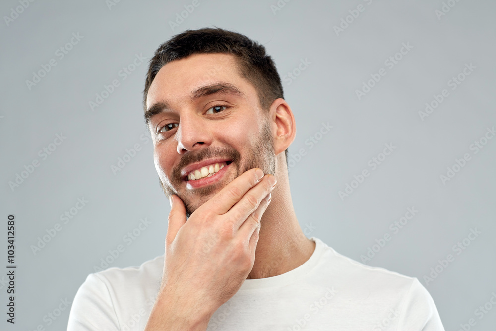 happy young man touching his face or beard happy young man touching his face or beard