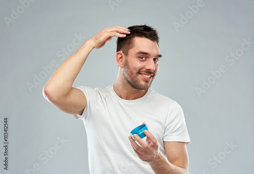 happy young man styling his hair with wax or gel photo
