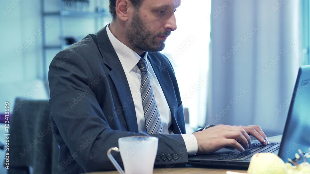 Young businessman working on laptop by table at home
Young businessman working on laptop by table at home