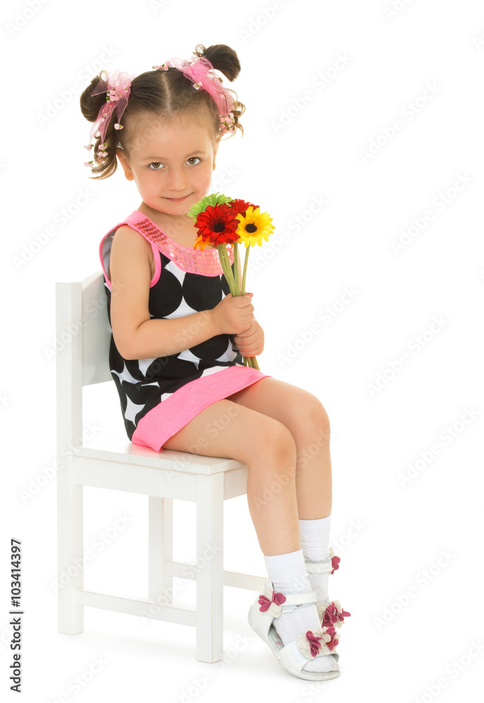 Cute little girl dressed in a short dress sits on a chair, and holding a  bouquet of flowers - Isolated on white background Stock Photo