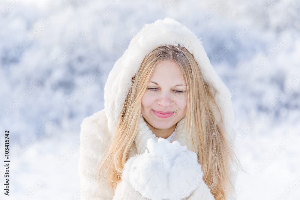 Smiling young blonde haired girl with snow in her hands in winter Smiling young blonde haired girl with snow in her hands in winter