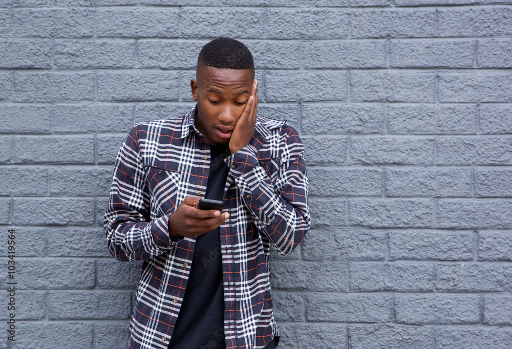 African man looking surprised while reading a text message African man looking surprised while reading a text message