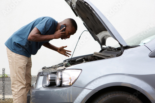 Young man calls for help with a stalled car